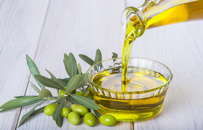 Dầu olive được rót từ trong chai ra một cái chén đặt cạnh những quả olive